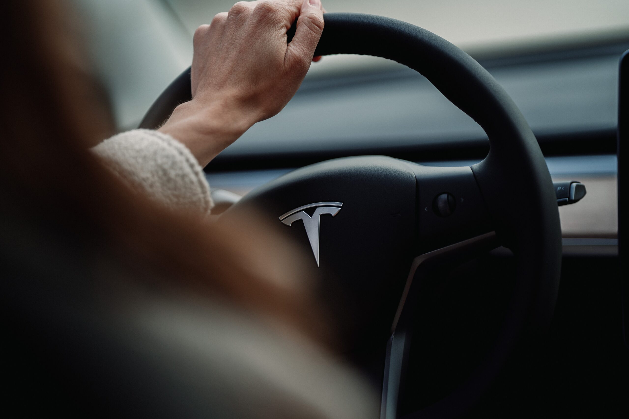 Dame som holder handen på rattet til en Tesla.